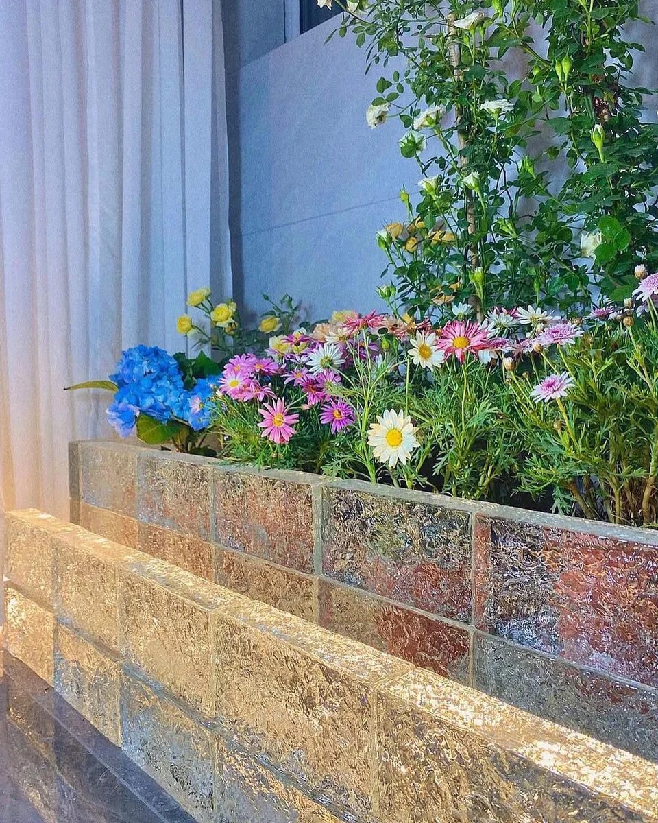 Un muro bajo de bloques de vidrio junto a plantas. Un ejemplo de vidrio como pequeño elemento decorativo.