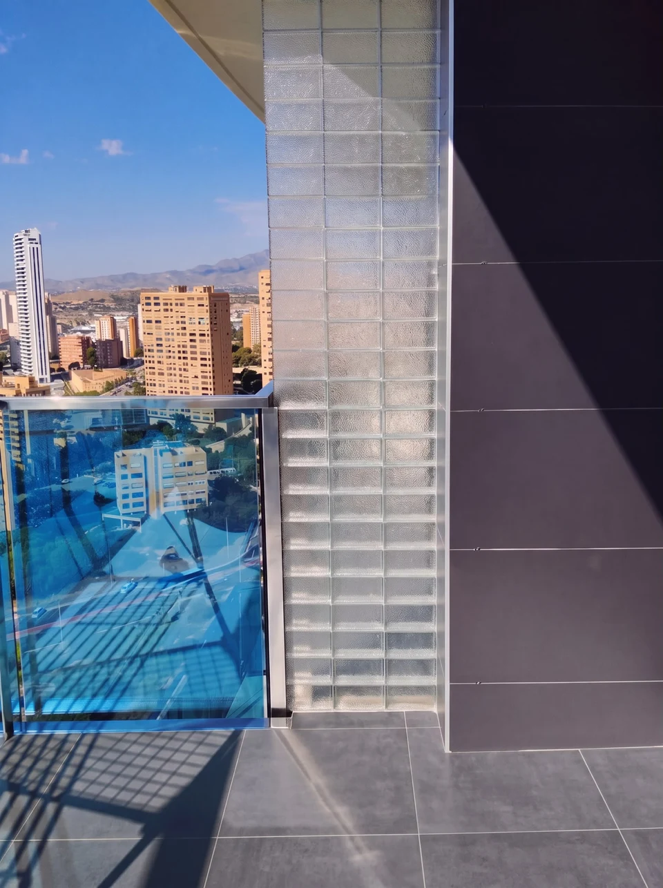 Un panel estrecho de bloques de vidrio en el balcón. La luz natural destaca la textura de cada bloque.